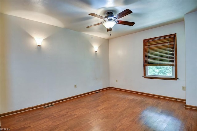 spare room with baseboards, ceiling fan, visible vents, and wood finished floors