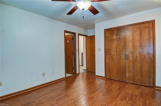 unfurnished bedroom featuring ceiling fan, a closet, baseboards, and wood finished floors