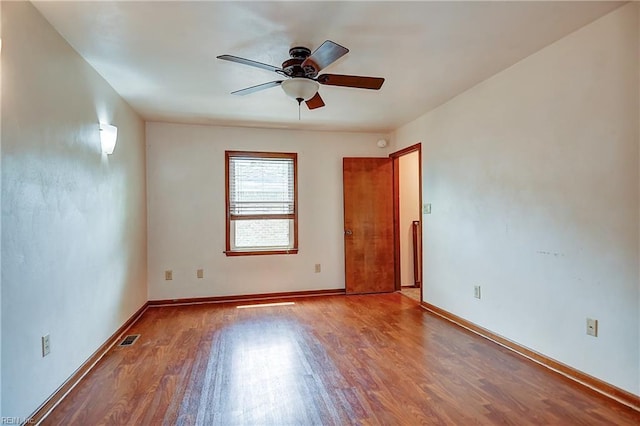 spare room with baseboards, ceiling fan, visible vents, and wood finished floors