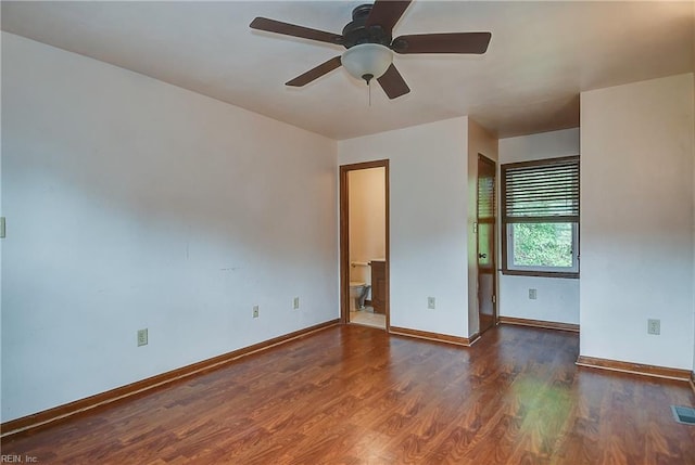 spare room with baseboards, a ceiling fan, visible vents, and wood finished floors