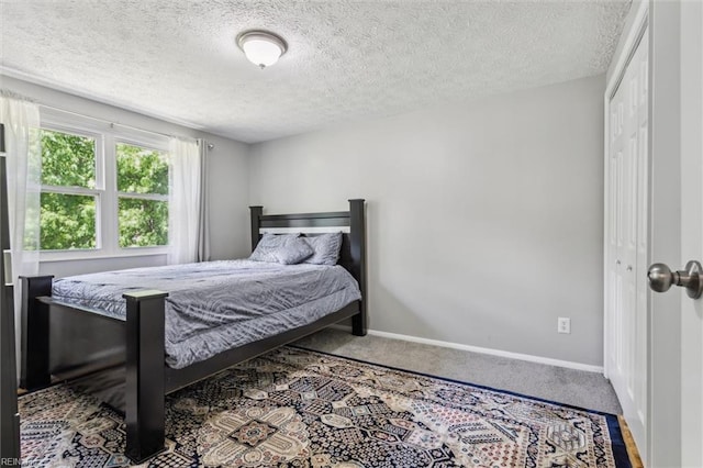 bedroom with baseboards, carpet floors, a closet, and a textured ceiling