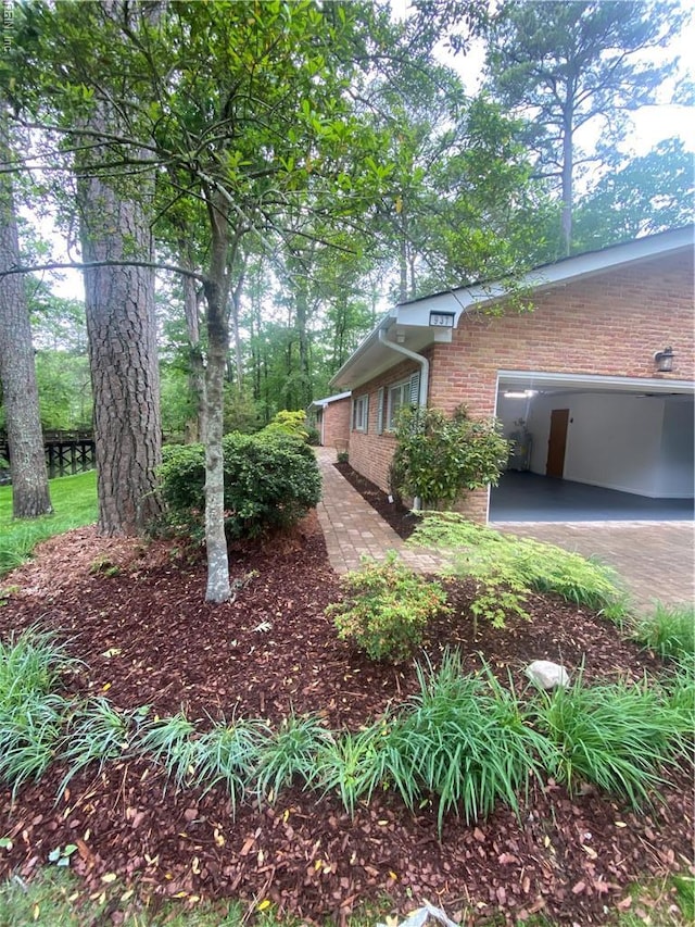 view of side of home with concrete driveway, brick siding, and an attached garage