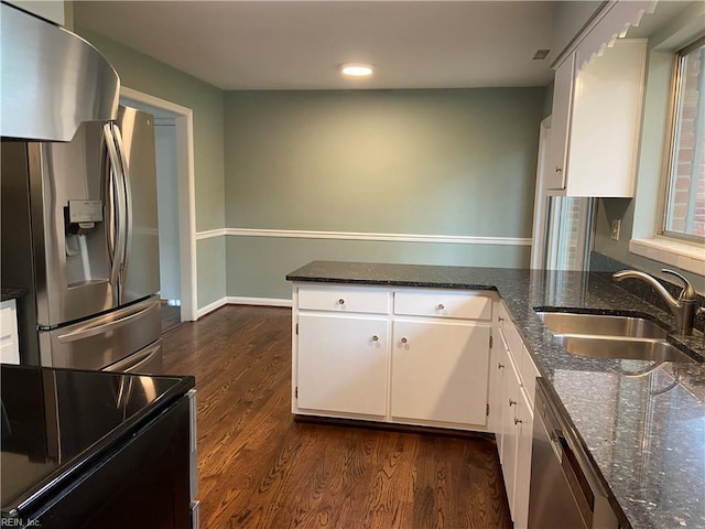 kitchen with a sink, dark stone countertops, dark wood-type flooring, white cabinets, and appliances with stainless steel finishes