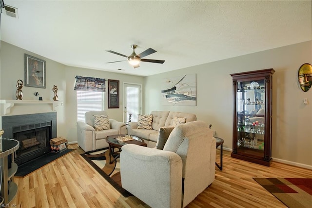 living area with visible vents, a ceiling fan, wood finished floors, and a fireplace