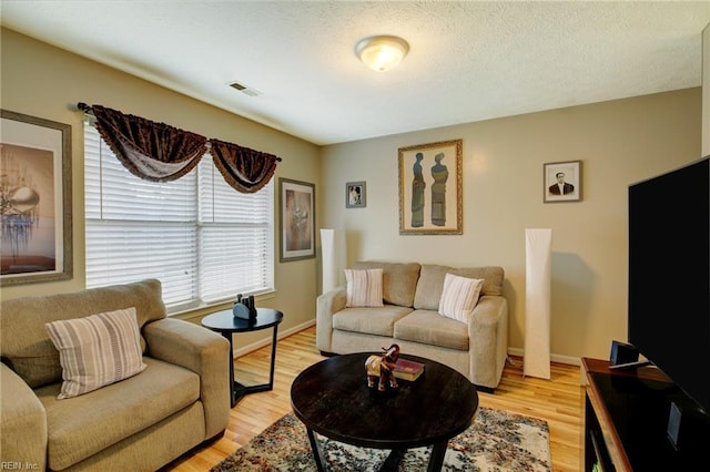 living area with light wood-style floors, baseboards, and visible vents