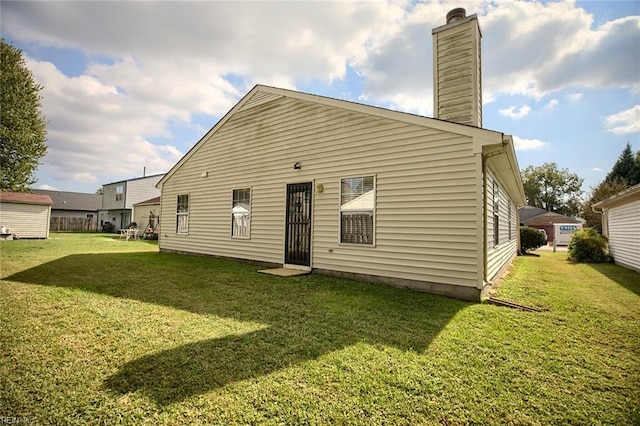 rear view of house with a lawn and a chimney