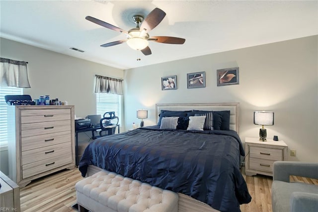 bedroom featuring a ceiling fan, visible vents, and light wood finished floors