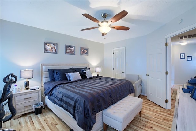 bedroom featuring light wood-style floors, a ceiling fan, and visible vents