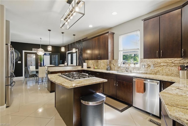 kitchen featuring a sink, a peninsula, decorative backsplash, dark brown cabinets, and appliances with stainless steel finishes
