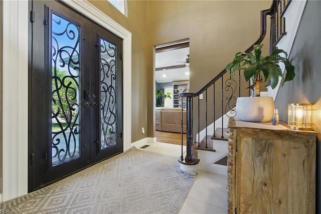 entrance foyer with stairway, tile patterned flooring, french doors, and a ceiling fan