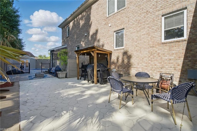 view of patio featuring outdoor dining space, area for grilling, fence, a shed, and an outdoor structure