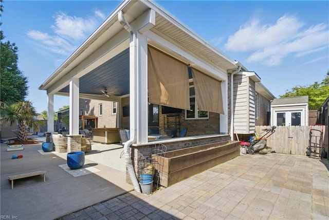 exterior space featuring a patio, brick siding, ceiling fan, and fence