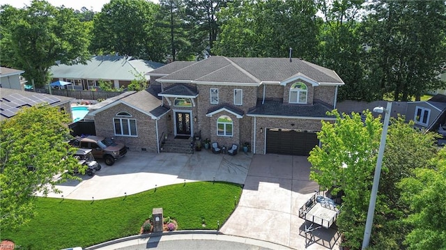 view of front facade with fence, brick siding, driveway, a garage, and a front lawn