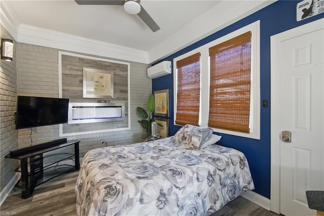 bedroom with an AC wall unit, baseboards, ceiling fan, wood finished floors, and a fireplace