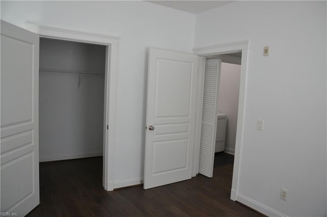 unfurnished bedroom with a closet, baseboards, and dark wood-style floors