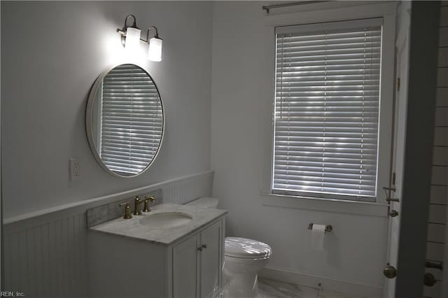 bathroom featuring vanity, toilet, a wainscoted wall, and marble finish floor
