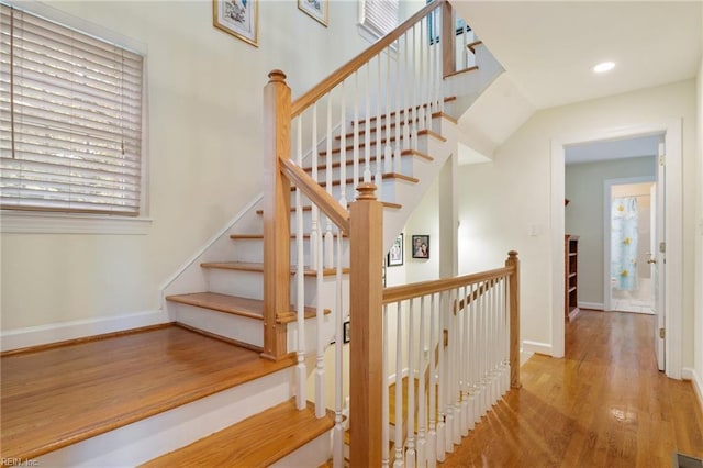 stairway featuring wood finished floors, baseboards, and recessed lighting