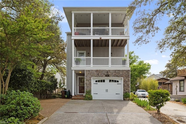 view of front of home with a balcony, stone siding, an attached garage, and concrete driveway