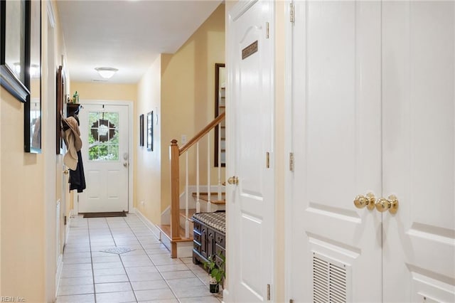 doorway with baseboards, stairs, visible vents, and light tile patterned flooring