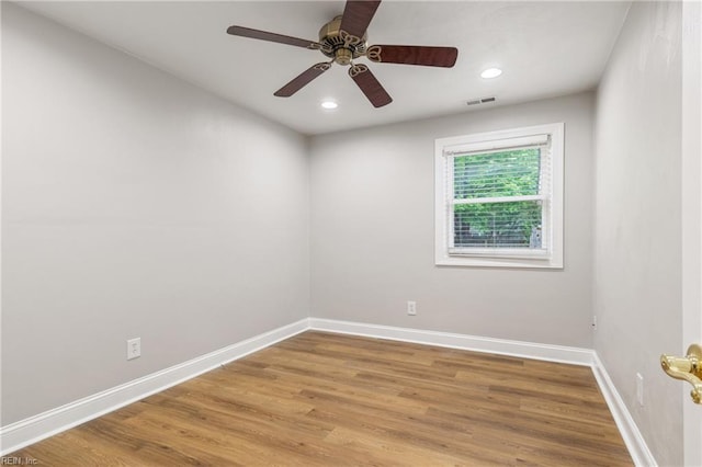 empty room with baseboards, a ceiling fan, visible vents, and wood finished floors