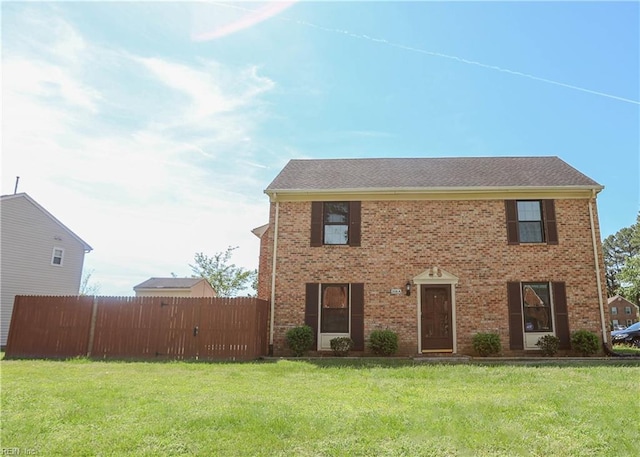 colonial-style house with a front yard, brick siding, and fence