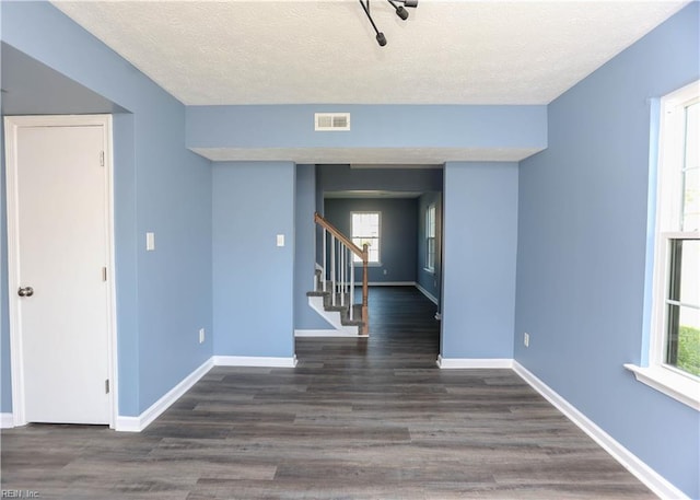 unfurnished room with baseboards, stairway, visible vents, and wood finished floors