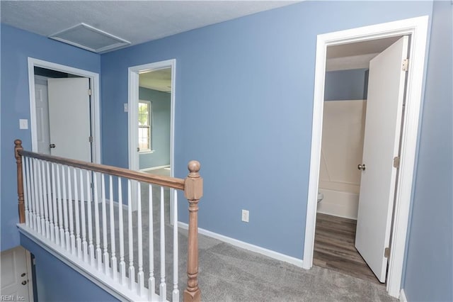 corridor featuring baseboards, carpet flooring, an upstairs landing, and attic access