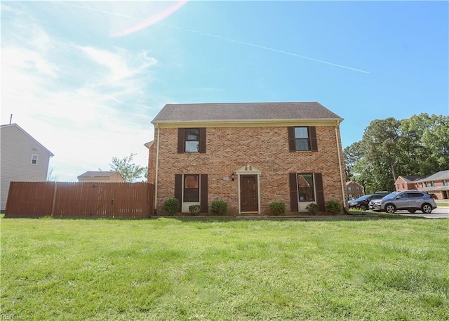 colonial house with fence, a front lawn, and brick siding