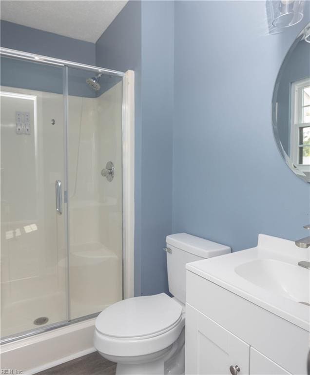 full bath featuring a stall shower, vanity, and toilet