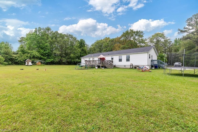 view of yard with an outbuilding, stairs, a trampoline, a wooden deck, and a storage shed