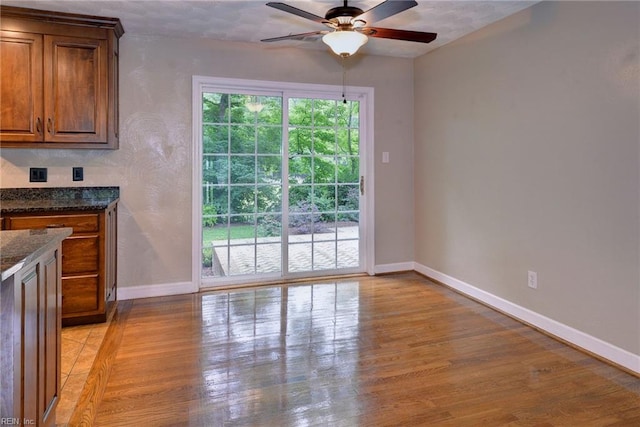 interior space with light wood finished floors, baseboards, and ceiling fan