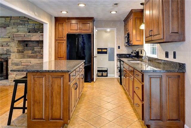 kitchen with brown cabinetry, a breakfast bar, black appliances, and a sink