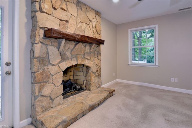 unfurnished living room with visible vents, baseboards, a stone fireplace, and carpet floors