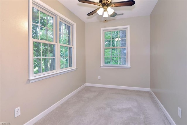 empty room with baseboards, light carpet, visible vents, and a ceiling fan