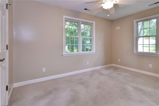 carpeted spare room with baseboards, ceiling fan, and visible vents