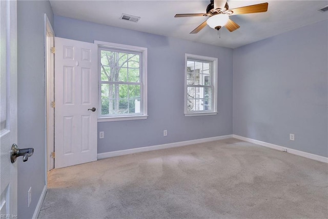 carpeted spare room featuring ceiling fan, baseboards, and visible vents