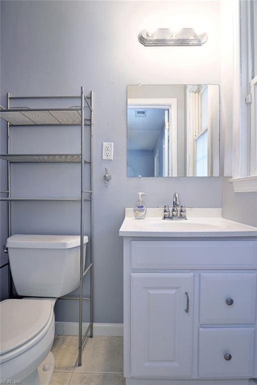 half bathroom featuring toilet, vanity, visible vents, tile patterned flooring, and baseboards