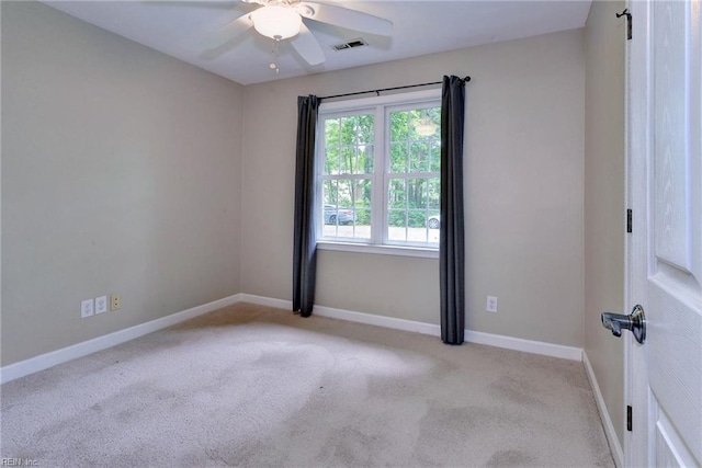 carpeted spare room featuring baseboards, ceiling fan, and visible vents