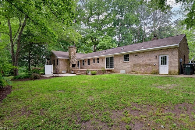 rear view of property featuring entry steps, a patio area, a chimney, and brick siding