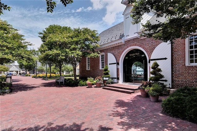 doorway to property featuring a high end roof and brick siding