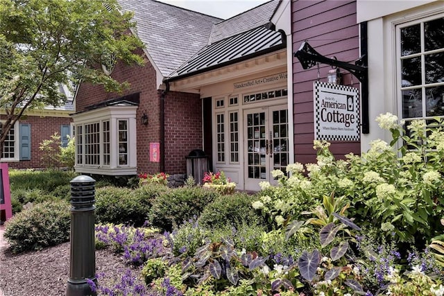 exterior space with a high end roof, brick siding, french doors, and a standing seam roof