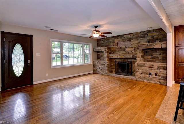 unfurnished living room with light wood finished floors, a ceiling fan, a fireplace, visible vents, and baseboards