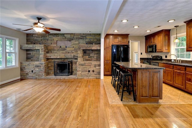 kitchen with a wealth of natural light, a kitchen breakfast bar, black appliances, and a sink