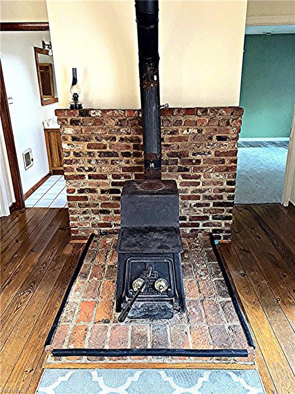 3810 Seaford Rd, Seaford, VA 23696 - room details with baseboards, a wood stove, and wood finished floors