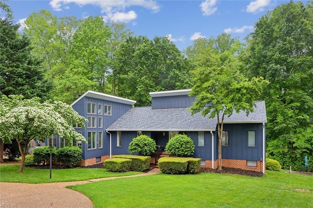 view of front facade featuring a shingled roof, a front lawn, crawl space, and board and batten siding