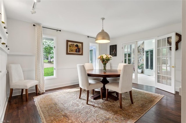 dining area featuring dark wood-type flooring, track lighting, and baseboards