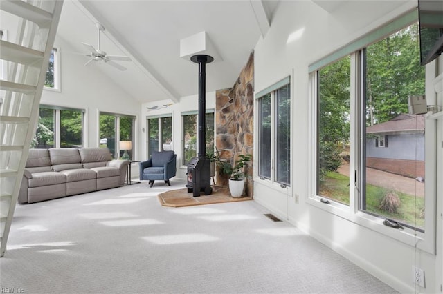 sunroom with a wood stove, carpet, healthy amount of natural light, and high vaulted ceiling
