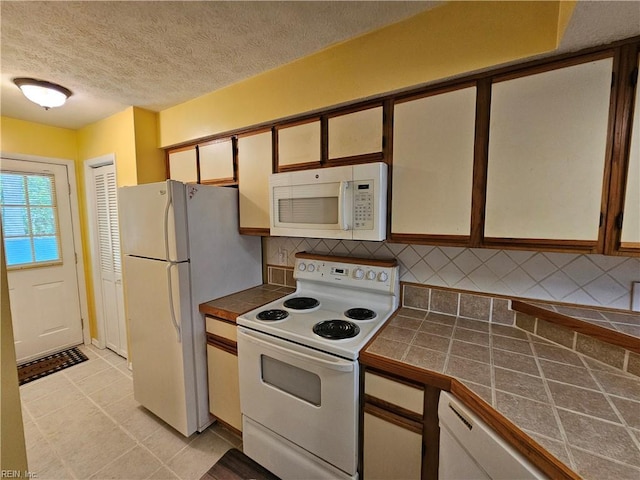 kitchen with white appliances, tile countertops, a textured ceiling, and tasteful backsplash