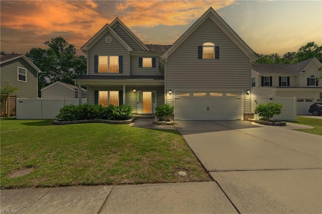 traditional-style home featuring fence, an attached garage, driveway, and a front yard