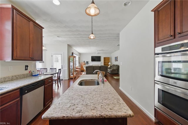 kitchen featuring appliances with stainless steel finishes, dark wood-style flooring, open floor plan, and a sink